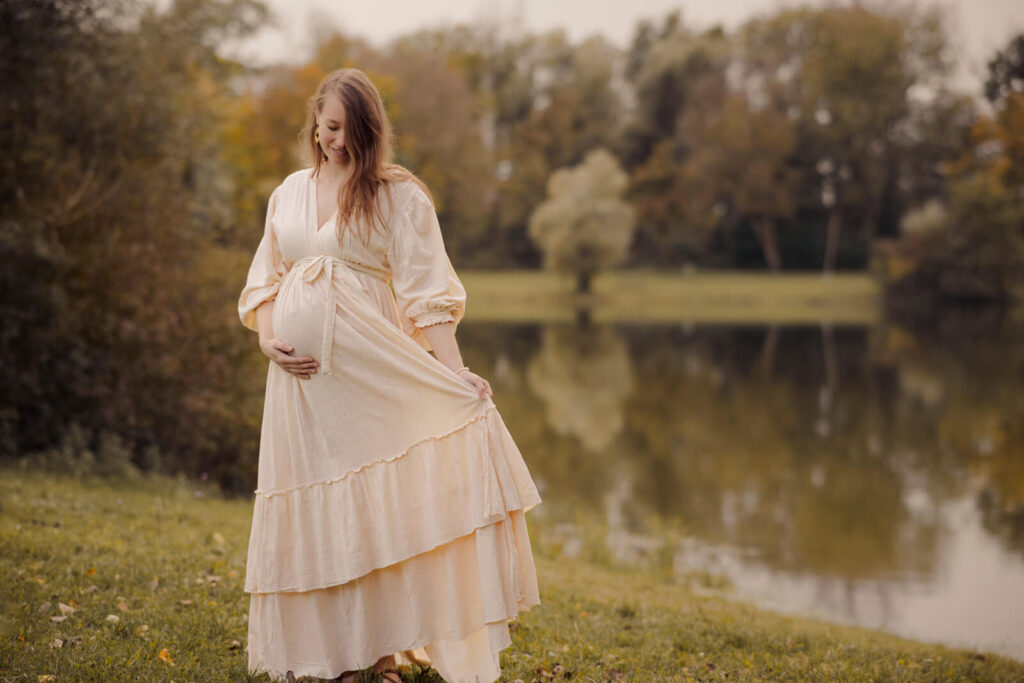 Verspielte Geste der werdenden Mama. Hält ihr Kleid etwas zur Seite.